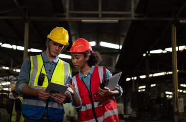 Yabancı mühendis eski makine fabrikasını teftiş etmeye geldi. Afrikalı bir kadın tamirci, eski makinelerin onarımının detaylarını ve ilerleme raporlarını açıklıyor..