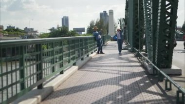 Yaşlı çiftler Tayland 'ın Bangkok kentindeki eski demir köprü (Phra Phutthayotfa Köprüsü) üzerinde seyahat ederler.