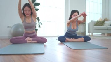 Asyalı genç kadınlar tatillerinde evlerinde yoga egzersizleri yapıyorlar.