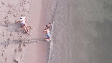 Sahilde dinlenen bir ailenin üst görüntüsü.