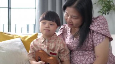 Annesiyle birlikte bir çocuk evin oturma odasında ukulele çalıyor.