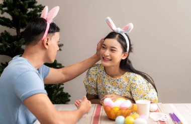 Genç bir çift Paskalya yumurtalarını tasarlıyor ve boyuyor.