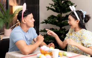 Genç bir çift Paskalya yumurtalarını tasarlıyor ve boyuyor.