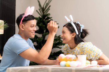 Genç bir çift Paskalya yumurtalarını tasarlıyor ve boyuyor.