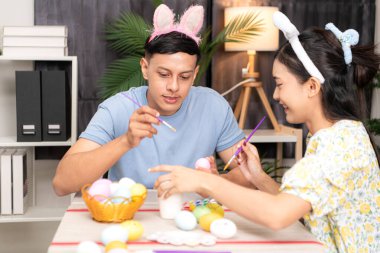 Genç bir çift Paskalya yumurtalarını tasarlıyor ve boyuyor.