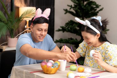 Genç bir çift Paskalya yumurtalarını tasarlıyor ve boyuyor.