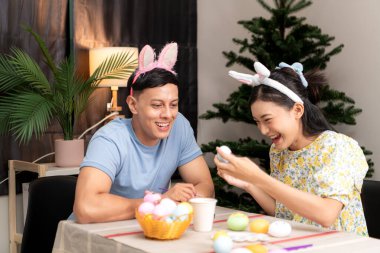Genç bir çift Paskalya yumurtalarını tasarlıyor ve boyuyor.