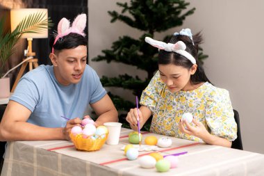 Genç bir çift Paskalya yumurtalarını tasarlıyor ve boyuyor.