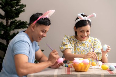 Genç bir çift Paskalya yumurtalarını tasarlıyor ve boyuyor.