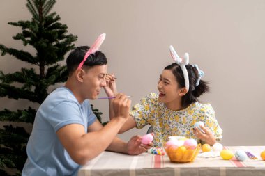 Genç bir çift Paskalya yumurtalarını tasarlıyor ve boyuyor.