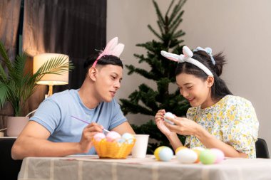 Genç bir çift Paskalya yumurtalarını tasarlıyor ve boyuyor.