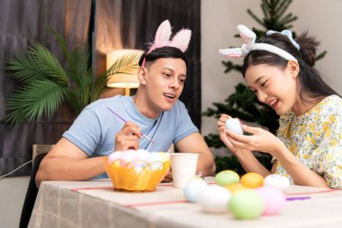 Genç bir çift Paskalya yumurtalarını tasarlıyor ve boyuyor.