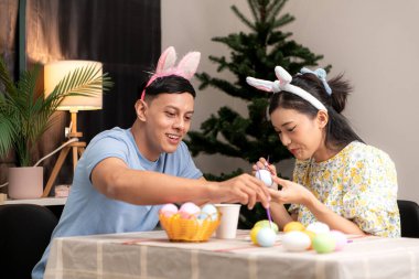 Genç bir çift Paskalya yumurtalarını tasarlıyor ve boyuyor.