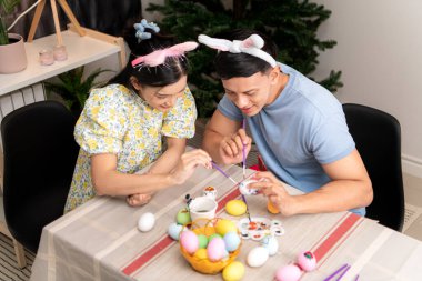 Genç bir çift Paskalya yumurtalarını tasarlıyor ve boyuyor.