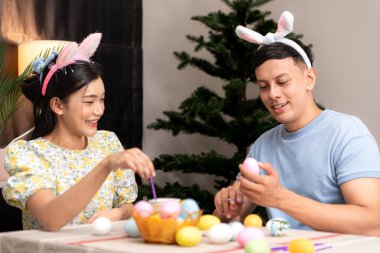 Genç bir çift Paskalya yumurtalarını tasarlıyor ve boyuyor.
