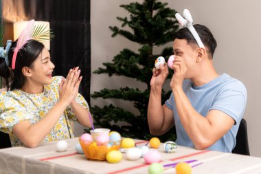 Genç bir çift Paskalya yumurtalarını tasarlıyor ve boyuyor.