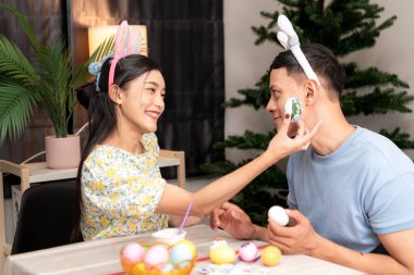 Genç bir çift Paskalya yumurtalarını tasarlıyor ve boyuyor.
