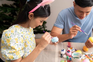 Genç bir çift Paskalya yumurtalarını tasarlıyor ve boyuyor.