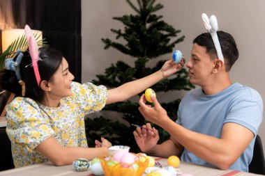 Genç bir çift Paskalya yumurtalarını tasarlıyor ve boyuyor.