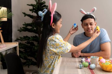 Genç bir çift Paskalya yumurtalarını tasarlıyor ve boyuyor.