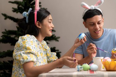 Genç bir çift Paskalya yumurtalarını tasarlıyor ve boyuyor.