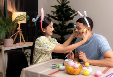 Genç bir çift Paskalya yumurtalarını tasarlıyor ve boyuyor.