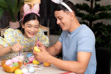 Genç bir çift Paskalya yumurtalarını tasarlıyor ve boyuyor.