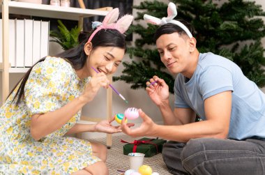 Genç bir çift Paskalya yumurtalarını tasarlıyor ve boyuyor.