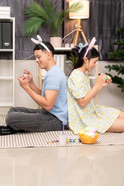 Genç bir çift Paskalya yumurtalarını tasarlıyor ve boyuyor.