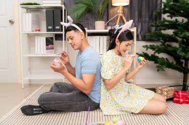 Genç bir çift Paskalya yumurtalarını tasarlıyor ve boyuyor.