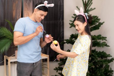 Genç bir çift Paskalya yumurtalarını tasarlıyor ve boyuyor.