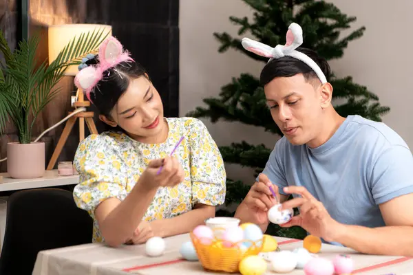 Genç bir çift Paskalya yumurtalarını tasarlıyor ve boyuyor.