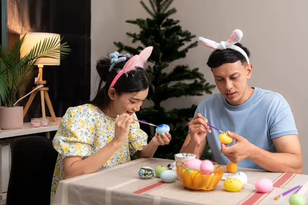 Genç bir çift Paskalya yumurtalarını tasarlıyor ve boyuyor.