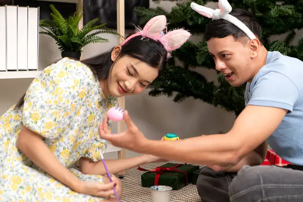 Genç bir çift Paskalya yumurtalarını tasarlıyor ve boyuyor.