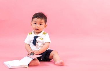 Pembe arka planda pilot kıyafetli çocuk portresi