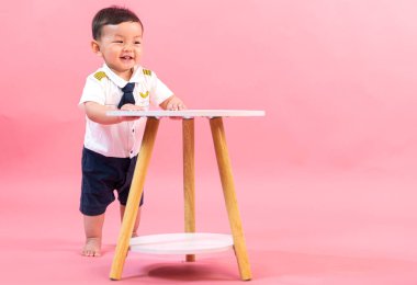 Pembe arka planda pilot kıyafetli çocuk portresi