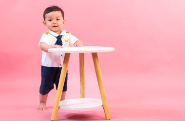 Pembe arka planda pilot kıyafetli çocuk portresi