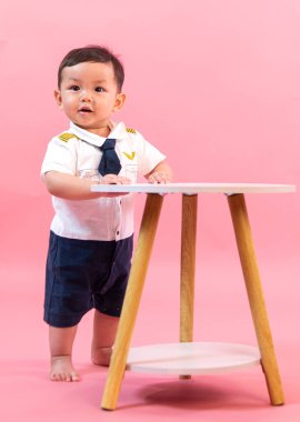 Pembe arka planda pilot kıyafetli çocuk portresi