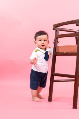 Pembe arka planda pilot kıyafetli çocuk portresi