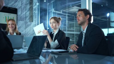 Konferans salonunda, bir grup işadamı takip toplantısını ve operasyonların sonuçlarını tartışıyor.