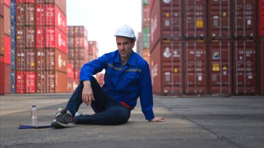 Konteynır deposunda çalışan bir işçi parlak güneş ışığında ve konteyner deposunun sıcak havasında çalışırken bayıldı.