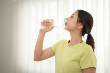 Genç spor kadınlarının portresi yoga antrenmanından sonra kırılıp su içiyor.