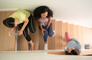 Bir grup genç spor kadını yoga antrenmanından sonra merdivenlerde su içiyor.