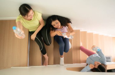 Bir grup genç spor kadını yoga antrenmanından sonra merdivenlerde su içiyor.