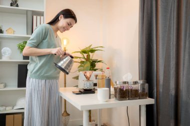 Genç bir kadın sabahları kendine damlatan bir kahve yapar.