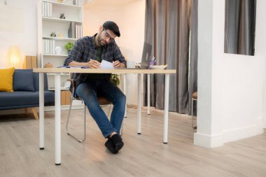 Evde kız arkadaşıyla bilgisayarla çalışırken gülümseyen genç bir serbest çalışanın portresi.