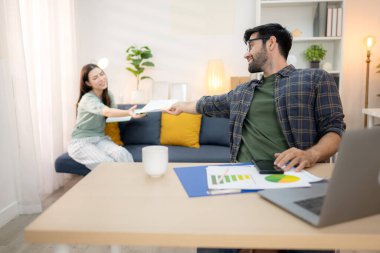 Evde kız arkadaşıyla bilgisayarla çalışırken gülümseyen genç bir serbest çalışanın portresi.