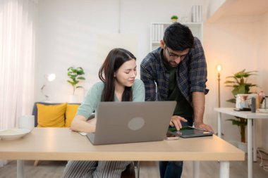 Evde erkek arkadaşıyla dizüstü bilgisayarla çalışırken gülümseyen genç bir serbest çalışanın portresi.