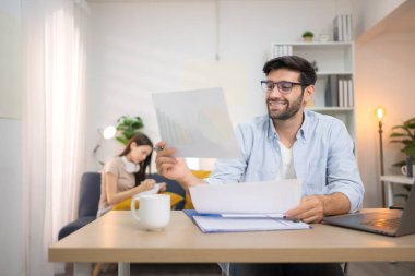 Evde dizüstü bilgisayarla çalışırken gülümseyen genç bir serbest çalışanın portresi