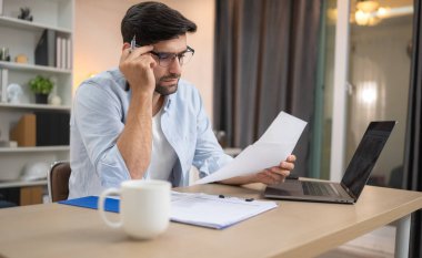 Evde dizüstü bilgisayarla çalışırken gülümseyen genç bir serbest çalışanın portresi